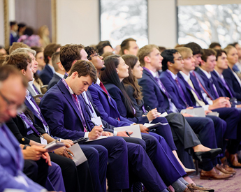 Attendees listening and taking notes during an Investment Strategies Conference presentation