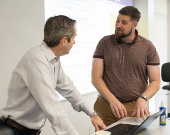 Two Executive Education participants having a discussion at a desk