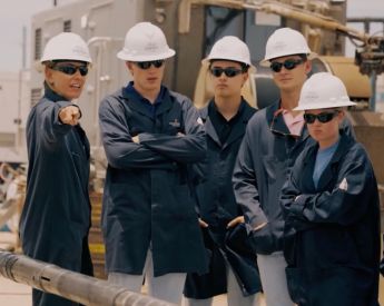 group students and advisor in the oilfield wearing helmets and protective gear