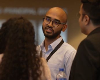 three students talking to each other in business attire at a conference