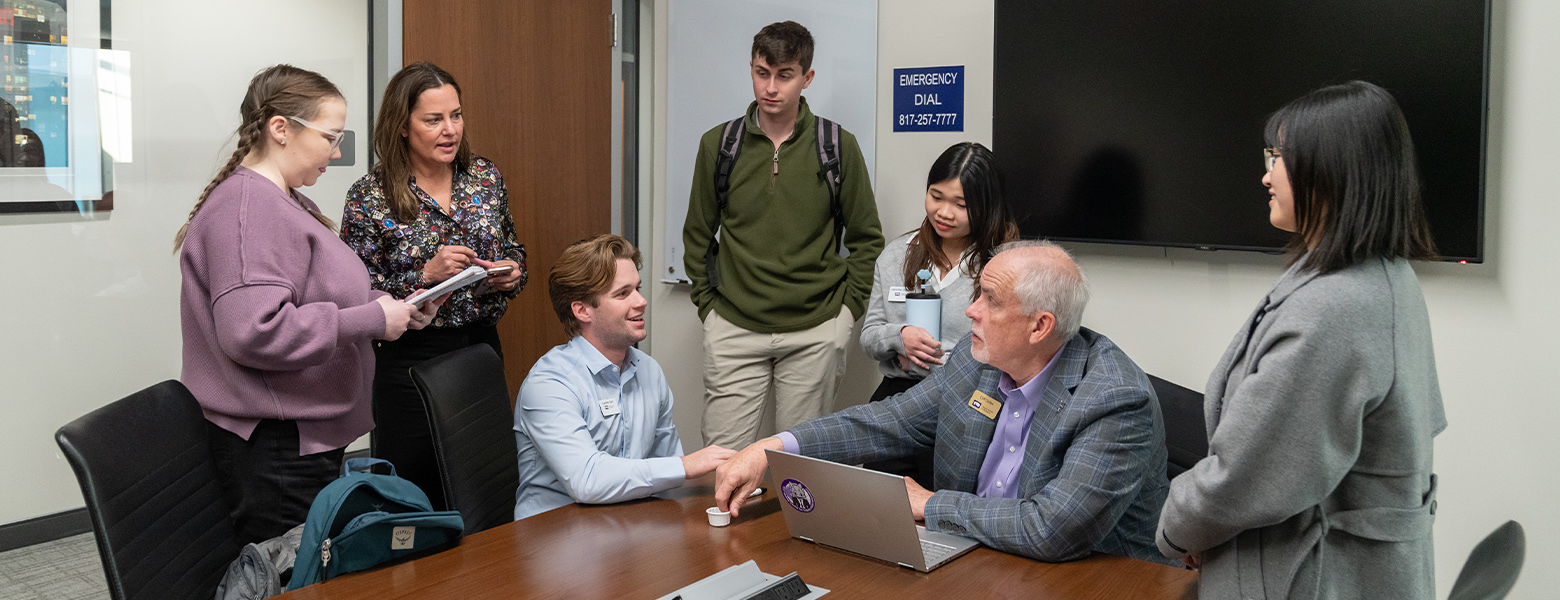 Group of students interacting with faculty partners before presentation