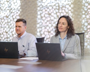 Neeley members listening and collaborating at a desk with computers