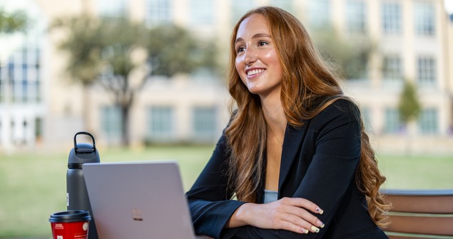 TCU student having conversation while working on computer