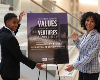 two women smiling and showcasing values and ventures showcase sign