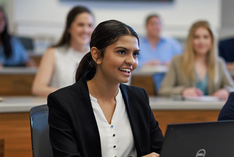 An Accounting student asks a question while working on a laptop in class