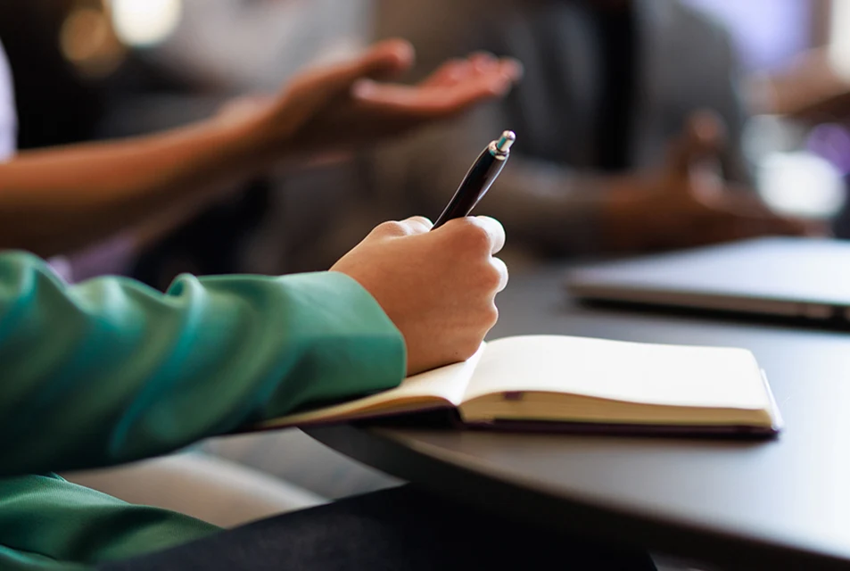Close-up of a student's hand as they take notes in a journal