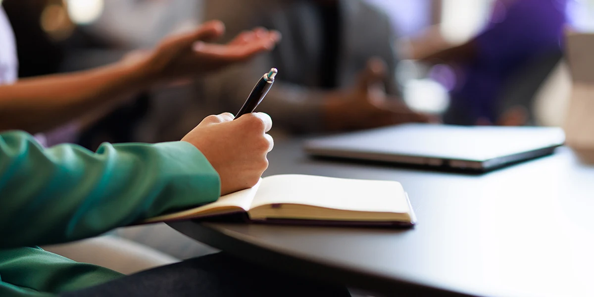 Close-up of a student's hand as they take notes in a journal