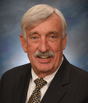 Tom Bates, wearing a black suite with black-and-gold tie
