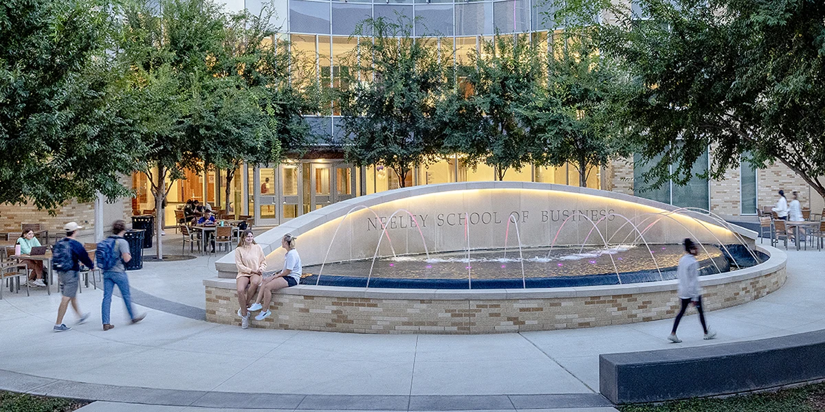 Neeley plaza, featuring the fountain, with students gathered to chat or walking to class