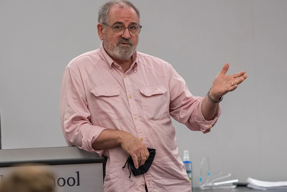 Michael Sherrod leans on the lecturn while addressing a class