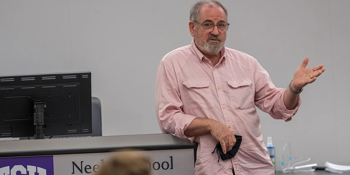 Michael Sherrod leans on the lecturn while addressing a class
