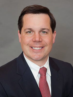 James Hill, wearing a black suite with a red tie