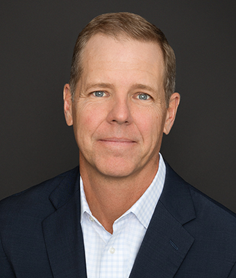 Chris Mitchell, wearing a dark suit with no tie