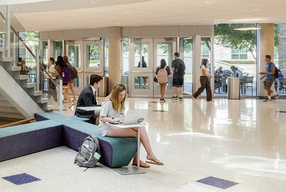 Students work on laptops in the Rotunda while others walk in and out