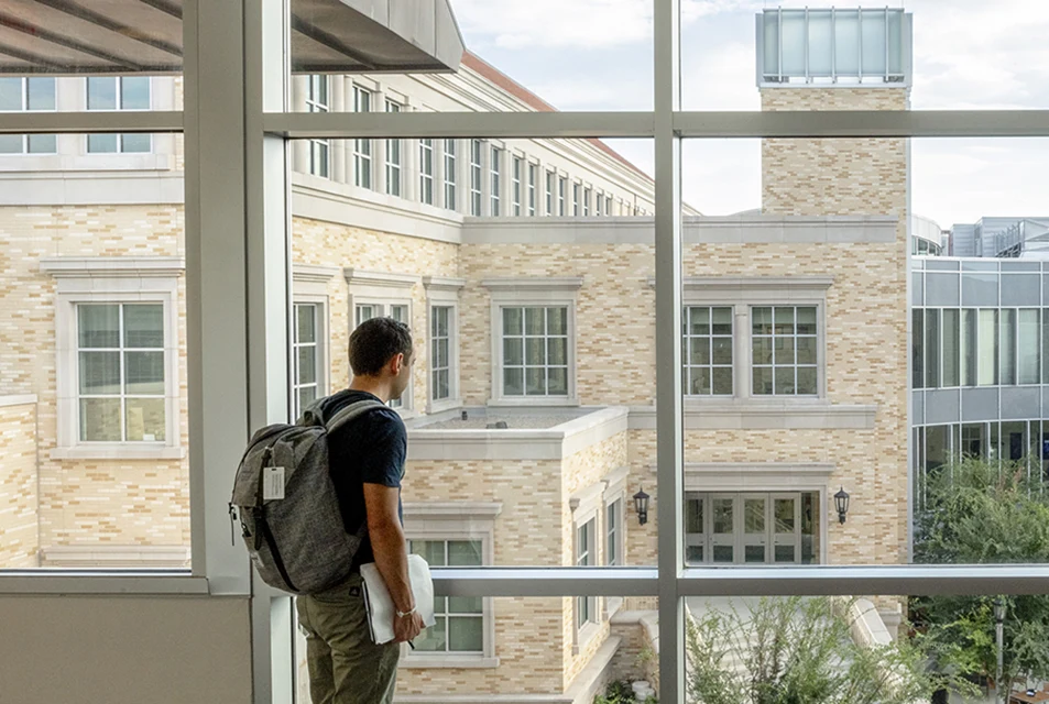 A student looks outside at the courtyard of the Neeley plaza